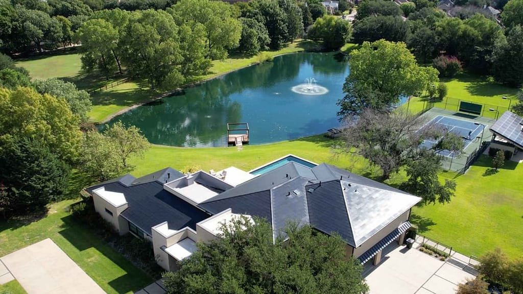 house with a pond powered by tesla solar roof and off-grid.