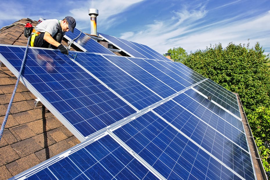Technician installing rooftop solar panels on a Texas home