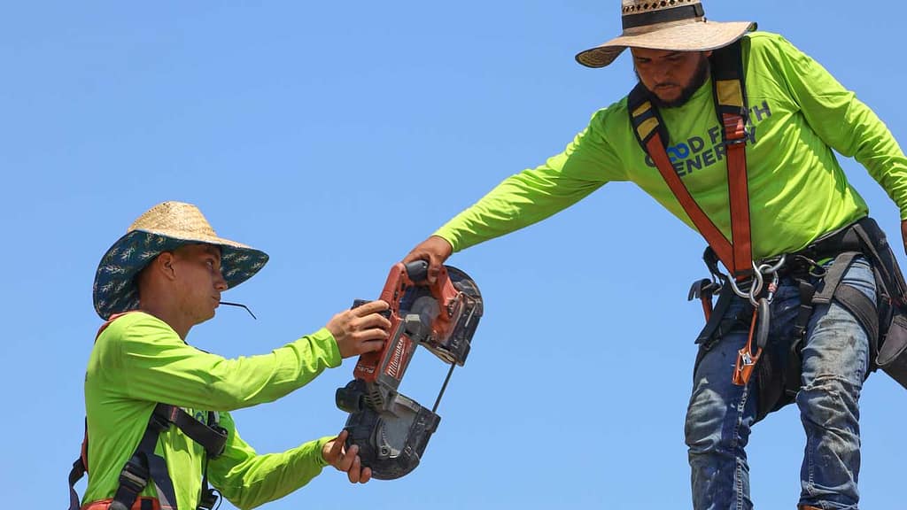 Two service professionals handing tools to each other