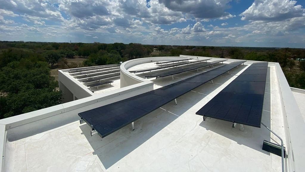roof mounted solar panels over cloudy blue sky and trees view