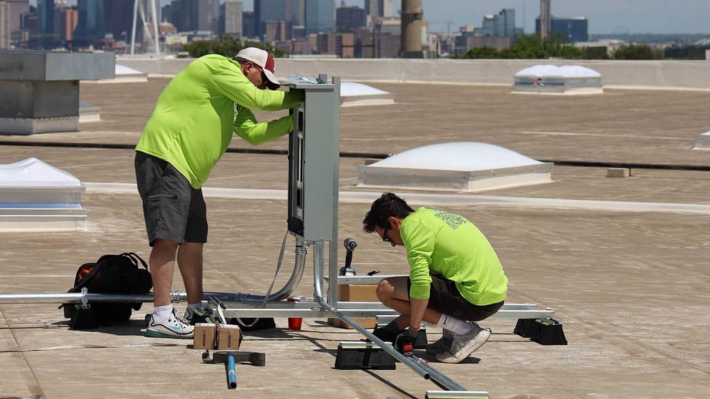 two solar installers wearing green long sleeves uniform