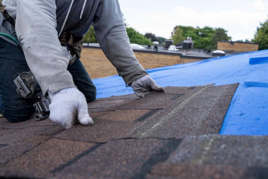 installer replacing asphalt shingle roof tiles